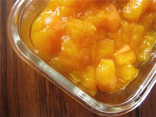 Homemade chunky apricot jam in a glass jar with spoon