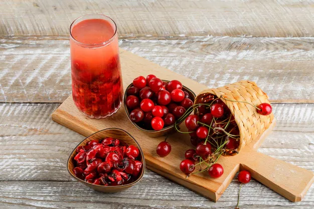 cranberry juice with berries in a woven basket at its one side on a cardboard.