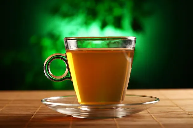 a cup of green tea placed on a wooden floor.
