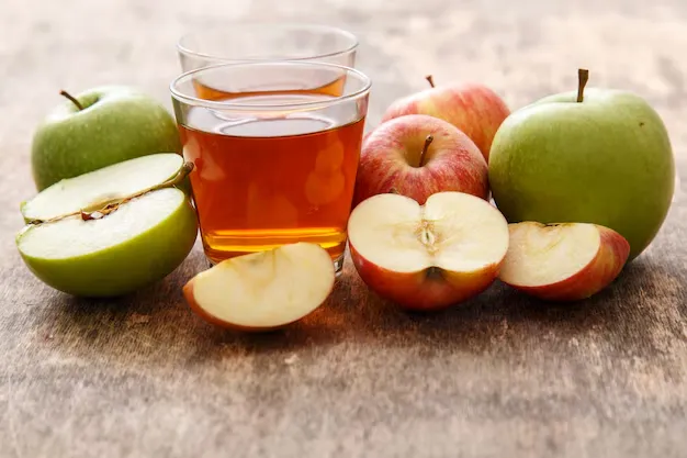 apple cider vinegar with scattered apples.