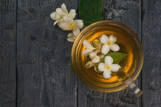 jasmine tea with jasmine flowers on a black wooden surface.