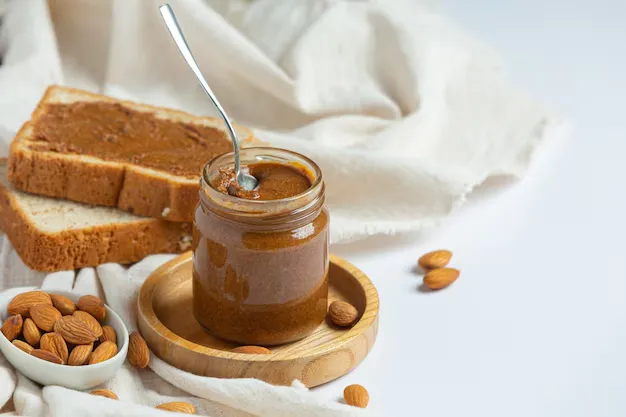 almond butter in a glass jar with bread slices.