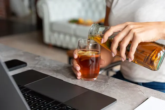 a woman pouring kombucha in a glass.