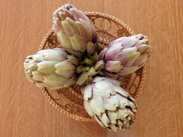 four artichokes in a basket on the wooden surface