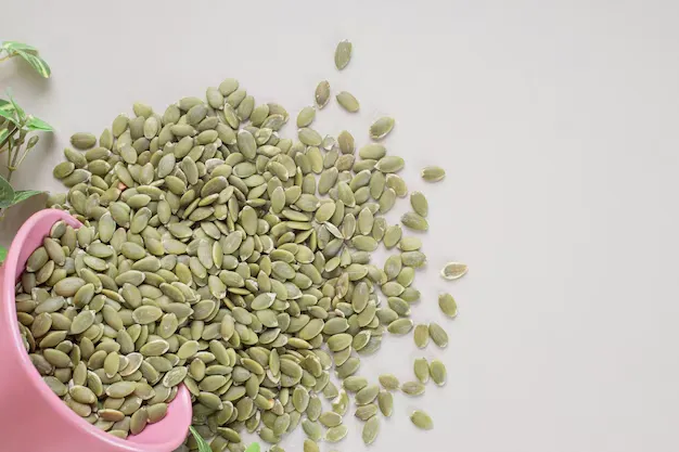 green pumpkin seeds coming out of pink bowl